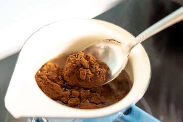 Place a spoonful of ground aromatic coffee into boiling water.