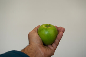 a man's hand holding a green apple