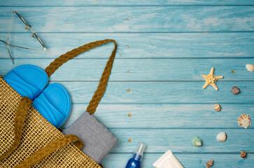 Beach bag with things on a blue wooden background. Top view, copy space