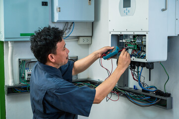Expertise solar engineer with electric meter checking with hybrid solar inverter during solar...