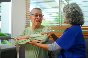 Fototapeta premium Senior male patient doing physical exercises with his physiotherapist at home. Rehabilitation and healthcare concept