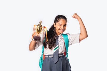 Excited Indian asian girl student in school uniform holding victory trophy in hand isolated on...