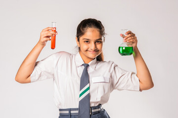 Obraz premium Indian asian small school girl in uniform holding flask with chemical against white background