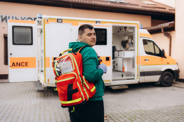 Male paramedic posing for camera, ambulance on background, professionalism