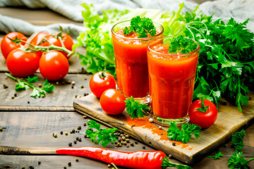 Tomato juice in glass with fresh tomatoes and parsley on wooden background