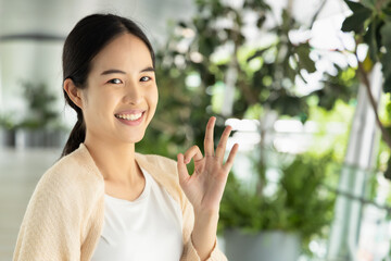 Smiling East Asian Woman Expressing Agreement with OK hand Gesture, concept image of Encouragement,...
