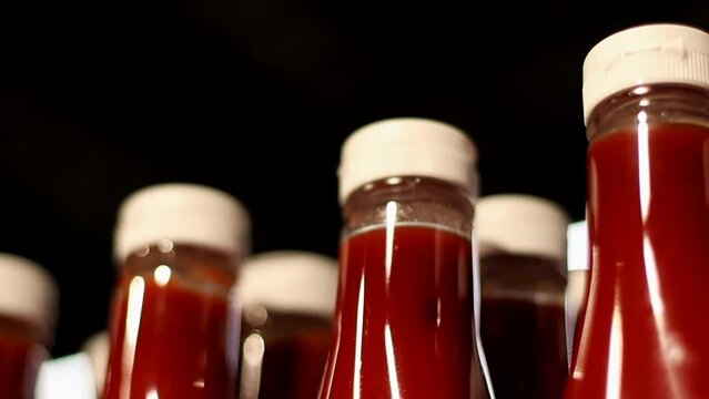 Row of Bottles with Tomato Sauce on Store Shelf. Plastic Packaging of Red Spicy ketchup in a Grocery Store. Close up