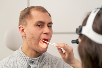 close-up in the clinic young doctor ear throat nose examines the patient s throat