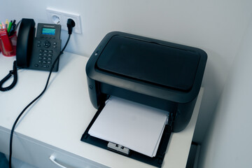 in a clinic in a bright modern office doctor’s workplace a black printer for printing