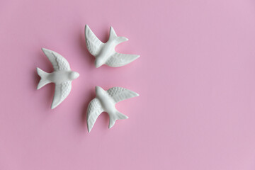 Three white swallows on pink background