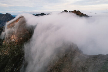 Aerial view of majestic mountain ridges at sunrise with falling fog from top of Pico do Areeiro, Madeira island, Portugal