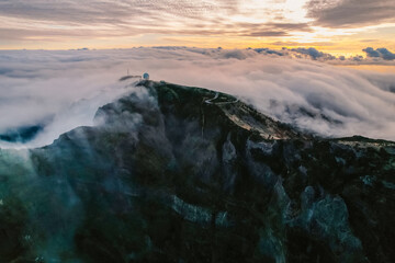 Aerial view of majestic mountain ridges at sunrise with falling fog from top of Pico do Areeiro, Madeira island, Portugal