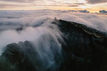 Aerial view of majestic mountain ridges at sunrise with falling fog from top of Pico do Areeiro, Madeira island, Portugal