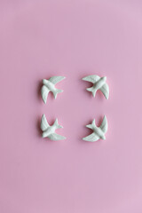 Four white swallows on pink background