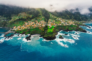 Aerial view of rough ocean with waves, volcanic beach and swiming pool in Seixal, Madeira, Portugal