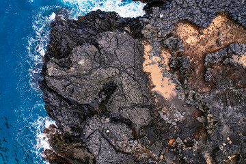 Aerial view of rough ocean with waves, volcanic beach in Porto da Cruz, Madeira, Portugal