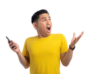 Excited young Asian man holding mobile phone and looking up with shocked expression isolated on white background
