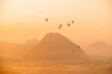 hot air balloons rising at golden sunrise in the mountain valley in Vang Vieng, the adventure...