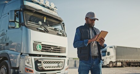 African American professional truck driver setting up navigation for destination. Checking his...