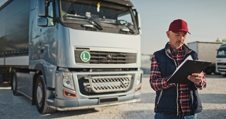 Portrait of delivery male worker holding black notepad in his arms. Adult truck driver in cap...