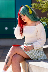 Nerdy girl with two-color hair listening to music in the park