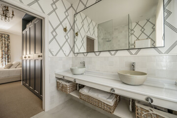 Beautiful bathroom with white marble countertops with individual terracotta sinks with chrome taps, wicker storage baskets and a large black framed mirror