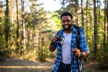 Young man enjoys using  binoculars and hiking  in nature.