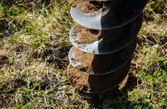 Drilling the ground with rig machine. The man drills the hole in land. Borering for the fence installation. Bore tool. Handy equipment. Portable manual earth auger for planting bushes and trees