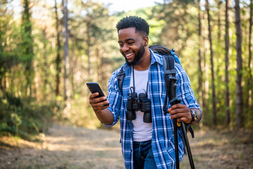 Young man enjoys hiking  and using mobile phone in nature.