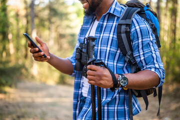 Young man enjoys hiking  and using mobile phone in nature.