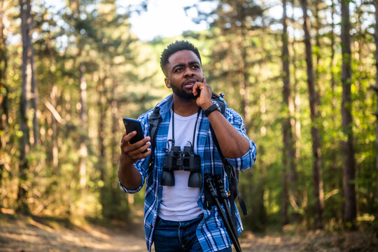 Worried hiker got lost and he is using a phone to find right direction while hiking in the nature.