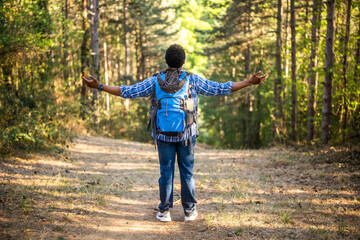 Happy man hiker with arms raised enjoys in the nature.