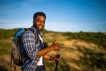 Young man enjoys hiking in nature and showing thumb up.
