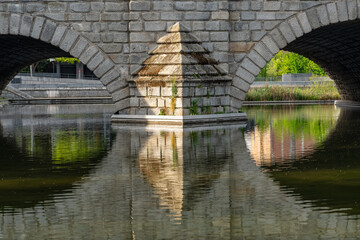 Fototapeta premium Stone arches of the old bridge reflected in the water of the Manzanares River, Madrid.