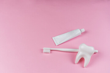 Mock-up healthy white tooth, toothbrush and denture for brushing teeth on pink background. The...