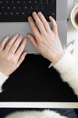 POV: Female hands typing on laptop keyboard. Top view of office desktop