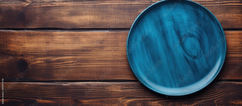 Aufkleber a blue plate rests on a wooden surface seen from above the wood s texture adds depth to the image le