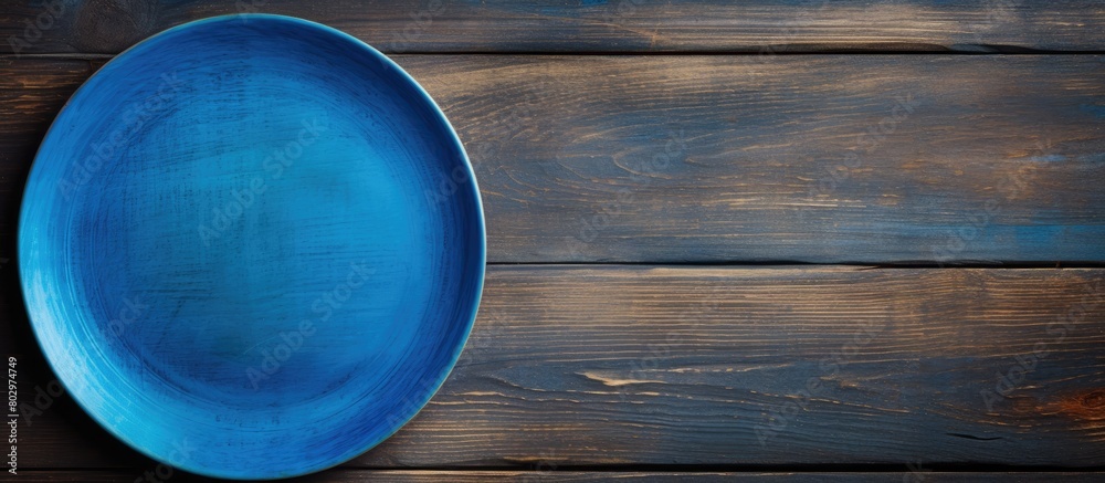 Poster a blue plate rests on a wooden surface seen from above the wood s texture adds depth to the image le
