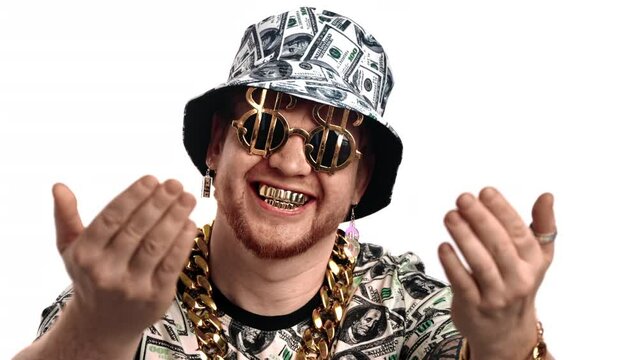 Funny guy with golden teeth and dollars on sunglasses looking at camera and beckoning by hands, face