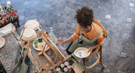 A young black artist paints acrylic paints on canvas with determination in her painting studio