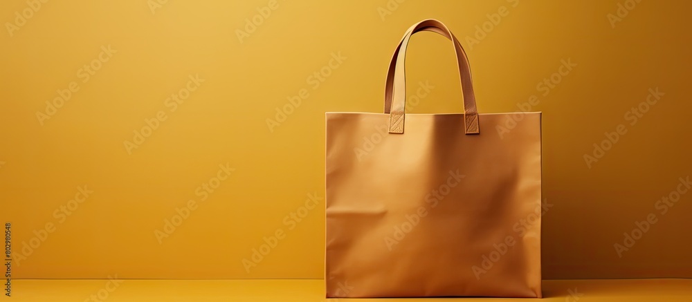 Poster A brown bag with an eco friendly design sits on a yellow background The bag is a luxury shopping bag with a handle loop There is empty space on the bag for text and a logo. with copy space image