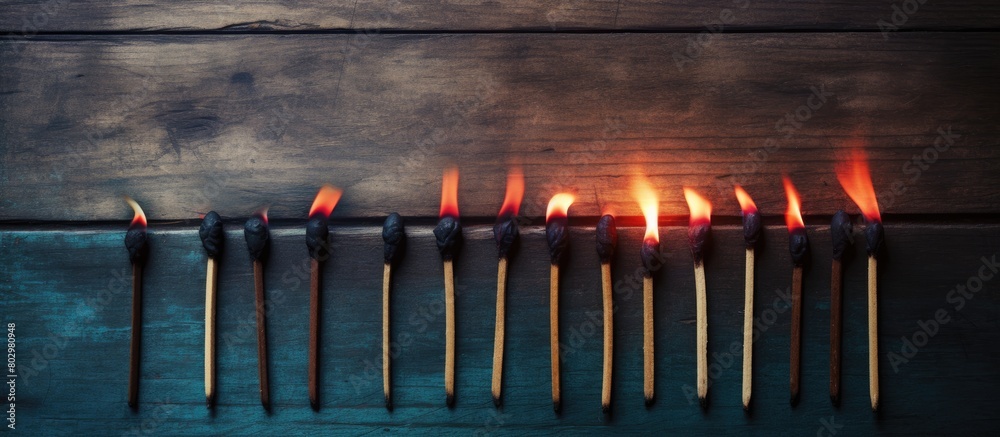 Poster A burnt match in a row of matches on a wooden background allowing for copy space image