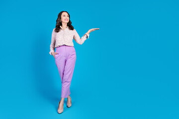 Full length photo of attractive senior woman look hold empty space dressed stylish formalwear clothes isolated on blue color background