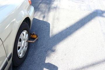 Car parking violation street area wheel locked with shadow on surface of street in Bangkok,...