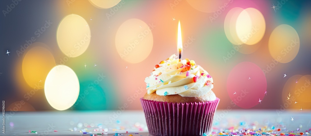 Aufkleber A birthday cupcake with a lit candle and colorful balloons serving as a blurred background providing space for text in the image. with copy space image. Place for adding text or design