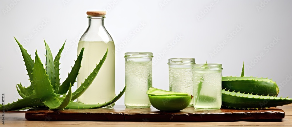 Poster a copy space image of a table showcasing peeled aloe vera with vibrant green leaves and bottles