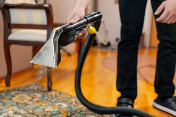 close up in the apartment a master cleaner waters the carpet with detergent from a professional...
