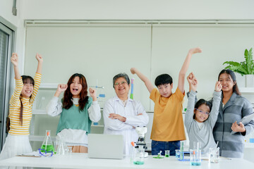 Students' learning in science classroom. Students and Asian teacher celebrate, arms raised, in...