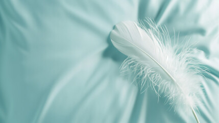 A fluffy white feather lies on a soft pillow. Pale green background with copy space