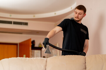 professional cleaning in an apartment cleaner wets a textile sofa before washing